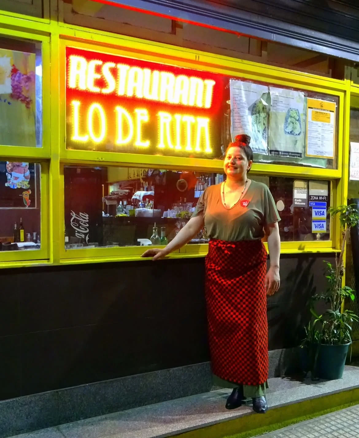 Rita frente al cartel de neón de Lo de Rita, de noche en Recoleta